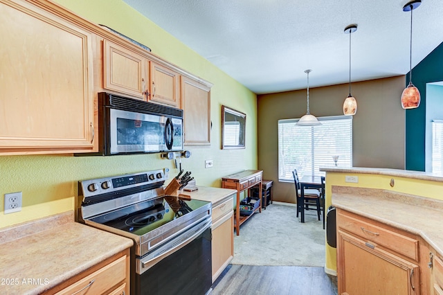kitchen with pendant lighting, light brown cabinetry, light wood-type flooring, light countertops, and appliances with stainless steel finishes