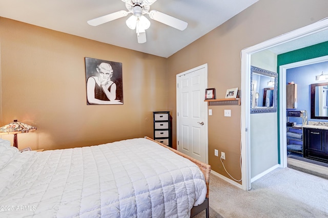 bedroom with baseboards, ceiling fan, ensuite bathroom, and light colored carpet