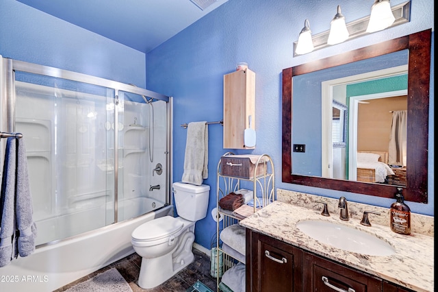 full bath featuring baseboards, vanity, toilet, and shower / bath combination with glass door