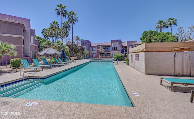 pool featuring a patio area, fence, and a residential view