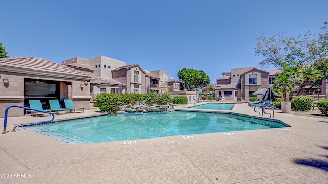 pool with a patio area, fence, and a residential view