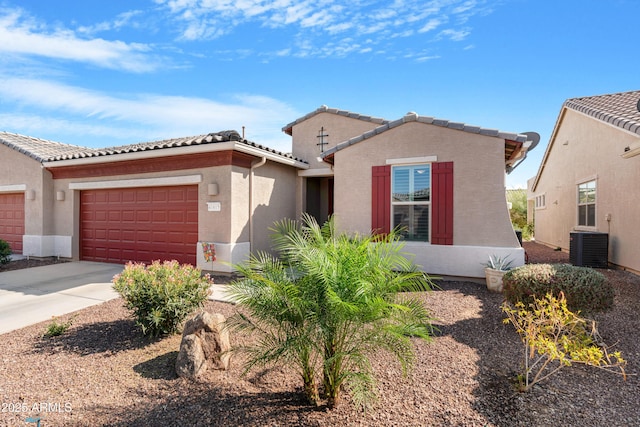 mediterranean / spanish-style home with central air condition unit, an attached garage, driveway, and a tiled roof