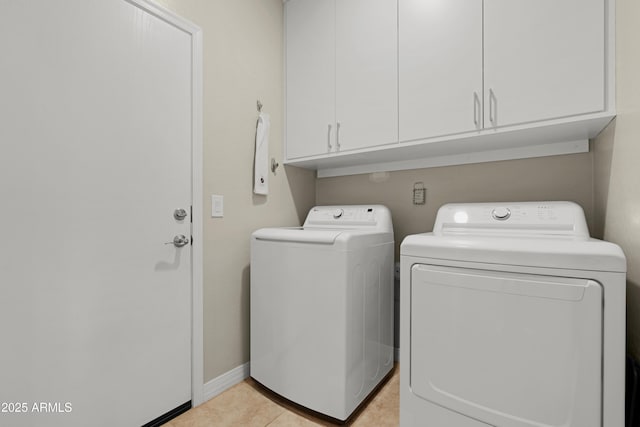 laundry area featuring light tile patterned floors, baseboards, cabinet space, and washer and clothes dryer