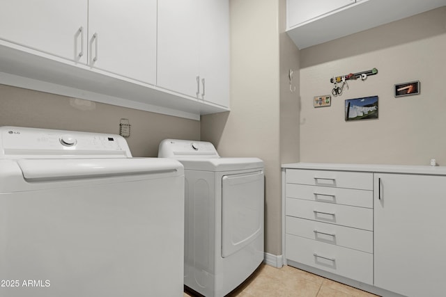 laundry room featuring baseboards, washer and clothes dryer, cabinet space, and light tile patterned floors