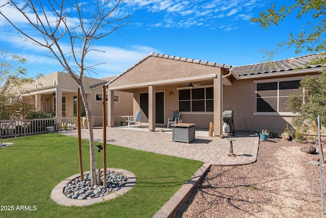 rear view of house with a ceiling fan, a lawn, a patio area, fence, and stucco siding
