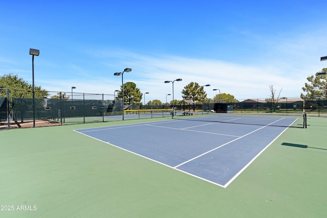 view of tennis court with community basketball court and fence