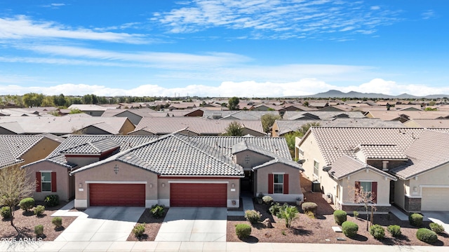 view of front of property with a residential view, an attached garage, a tile roof, stucco siding, and driveway