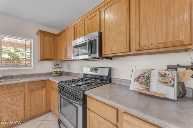 kitchen with a sink, light tile patterned floors, and stainless steel appliances