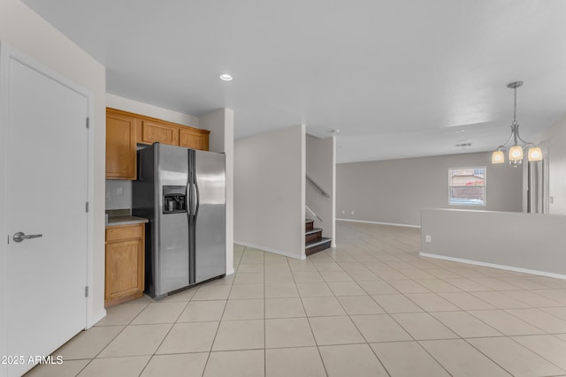 kitchen with brown cabinetry, baseboards, open floor plan, recessed lighting, and stainless steel fridge with ice dispenser