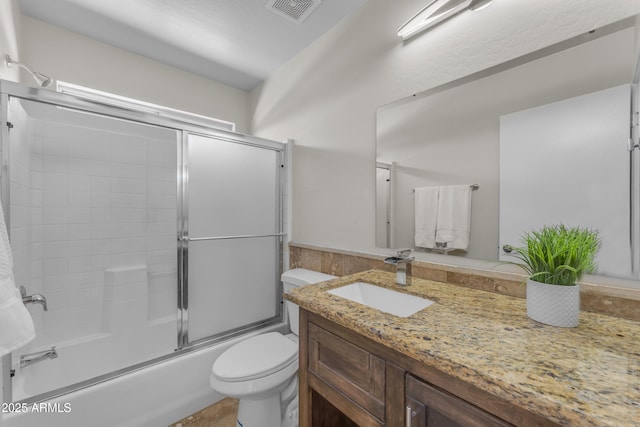 bathroom featuring vanity, combined bath / shower with glass door, toilet, and visible vents