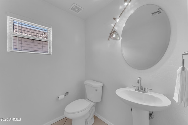 bathroom with a sink, toilet, tile patterned floors, baseboards, and visible vents