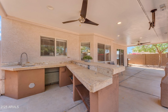 view of patio with fence, outdoor dry bar, a sink, and ceiling fan