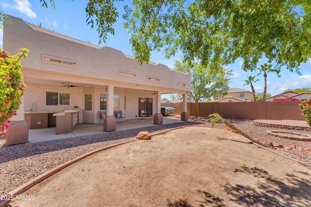 rear view of property with a fenced backyard, a patio area, stucco siding, and a sink