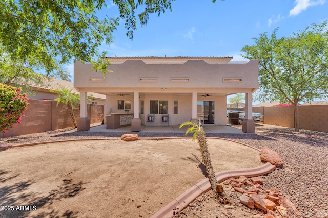 rear view of property with a fenced backyard, a ceiling fan, stucco siding, and a patio area