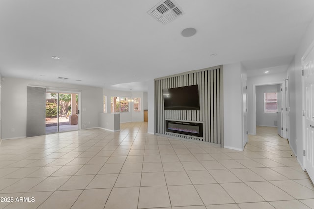 unfurnished living room with a glass covered fireplace, baseboards, light tile patterned flooring, and visible vents