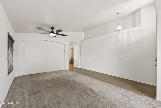13438 N 130th Ln, El Mirage, AZ 85335 - carpeted spare room featuring a ceiling fan, arched walkways, baseboards, and wood finished floors