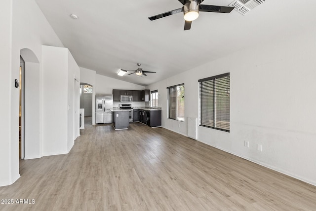 13438 N 130th Ln, El Mirage, AZ 85335 - unfurnished living room featuring a ceiling fan, vaulted ceiling, light wood-style flooring, arched walkways, and baseboards