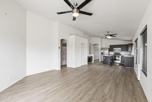 13438 N 130th Ln, El Mirage, AZ 85335 - unfurnished living room featuring ceiling fan, arched walkways, lofted ceiling, wood finished floors, and a sink
