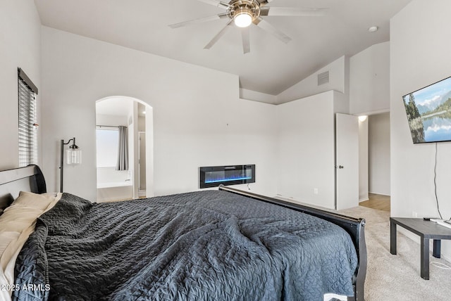 13438 N 130th Ln, El Mirage, AZ 85335 - carpeted bedroom with arched walkways, vaulted ceiling, a glass covered fireplace, a ceiling fan, and connected bathroom