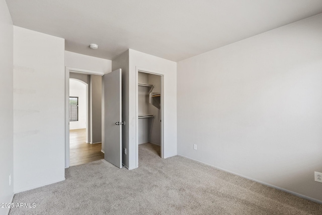13438 N 130th Ln, El Mirage, AZ 85335 - unfurnished bedroom with carpet flooring, arched walkways, a walk in closet, a closet, and baseboards
