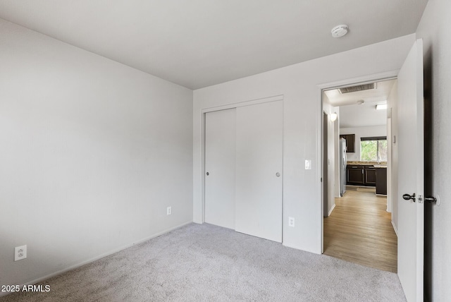 13438 N 130th Ln, El Mirage, AZ 85335 - unfurnished bedroom featuring carpet, a closet, baseboards, and freestanding refrigerator