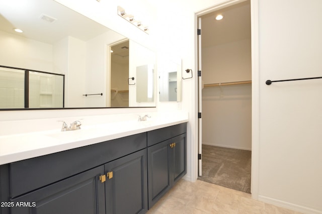 full bath featuring double vanity, recessed lighting, a spacious closet, an enclosed shower, and a sink