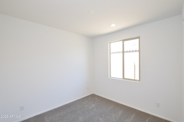 empty room featuring recessed lighting, dark carpet, and baseboards