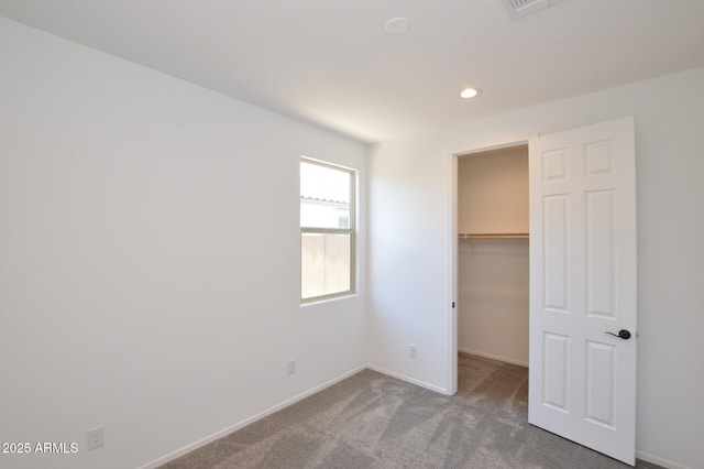 unfurnished bedroom featuring carpet, a walk in closet, recessed lighting, a closet, and baseboards