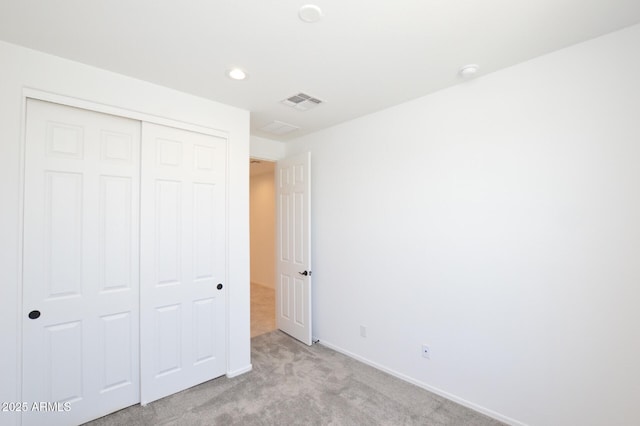 unfurnished bedroom with recessed lighting, a closet, light colored carpet, visible vents, and baseboards