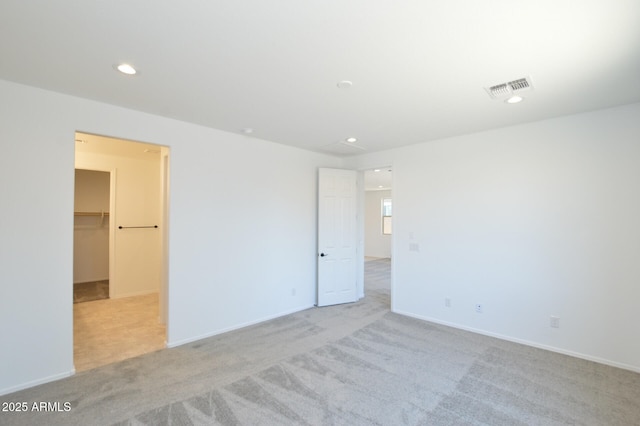 carpeted empty room with baseboards, visible vents, and recessed lighting