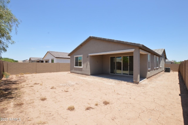 back of property with a fenced backyard, central AC unit, and stucco siding