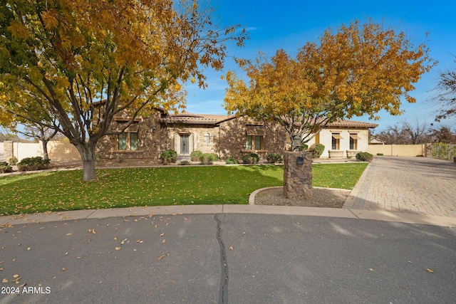 view of front of property with a tiled roof, a front yard, and fence