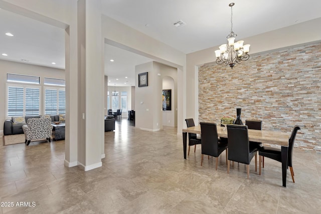 dining space featuring a chandelier, arched walkways, visible vents, and baseboards