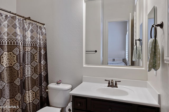 full bath featuring a textured wall, vanity, and toilet