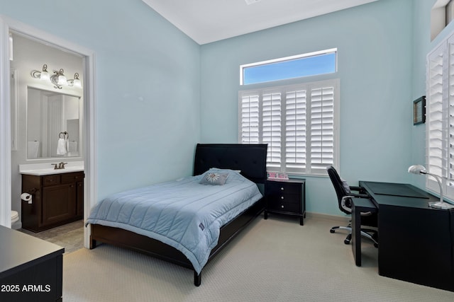 bedroom featuring ensuite bathroom, baseboards, a sink, and light colored carpet