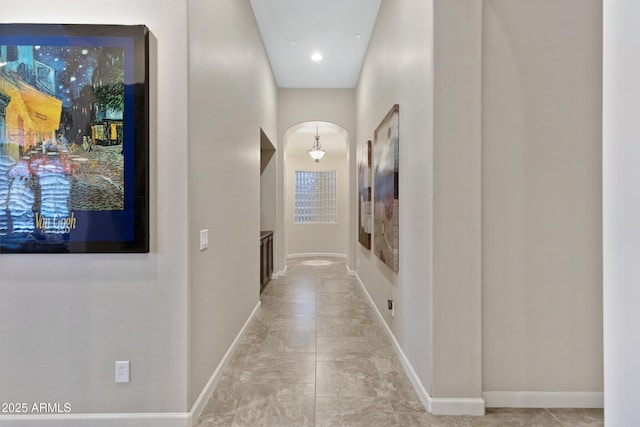 hall featuring baseboards and arched walkways