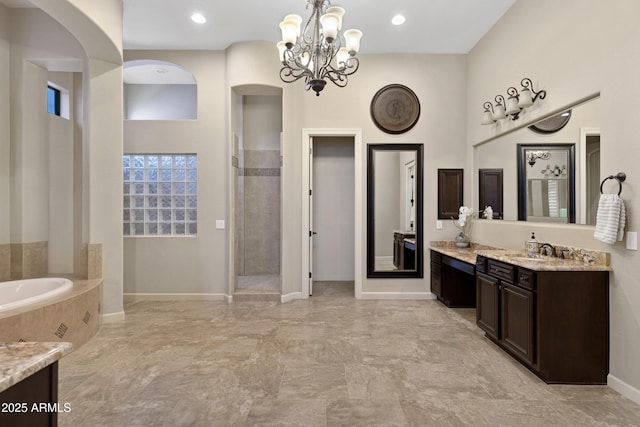 full bath with a garden tub, vanity, baseboards, tiled shower, and an inviting chandelier