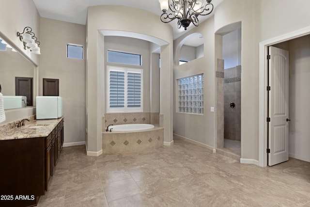 full bathroom featuring baseboards, vanity, a chandelier, a walk in shower, and a bath