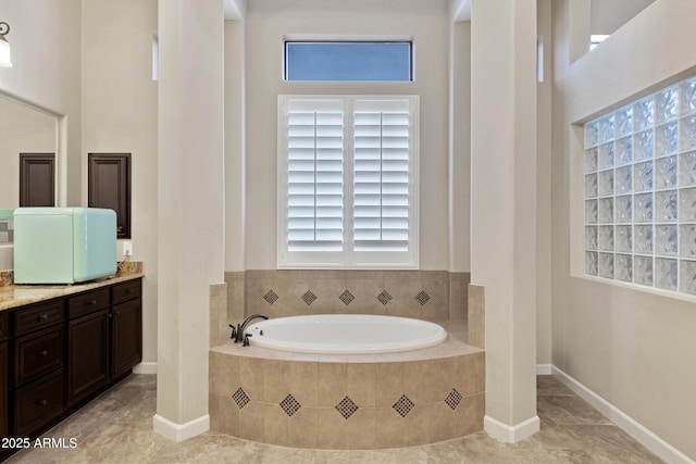 bathroom featuring a wealth of natural light, baseboards, a bath, and vanity