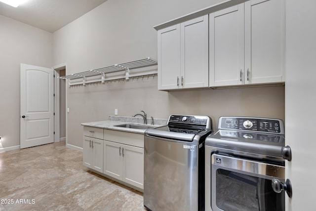 washroom with washing machine and clothes dryer, a sink, cabinet space, and baseboards