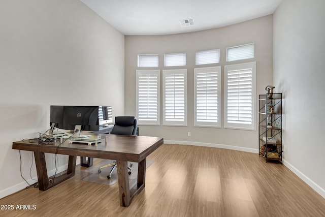 office space featuring light wood finished floors, visible vents, and baseboards