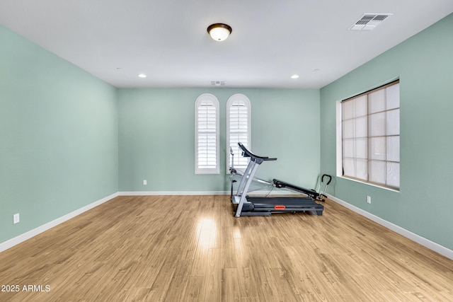 exercise room with light wood-style flooring, visible vents, and baseboards