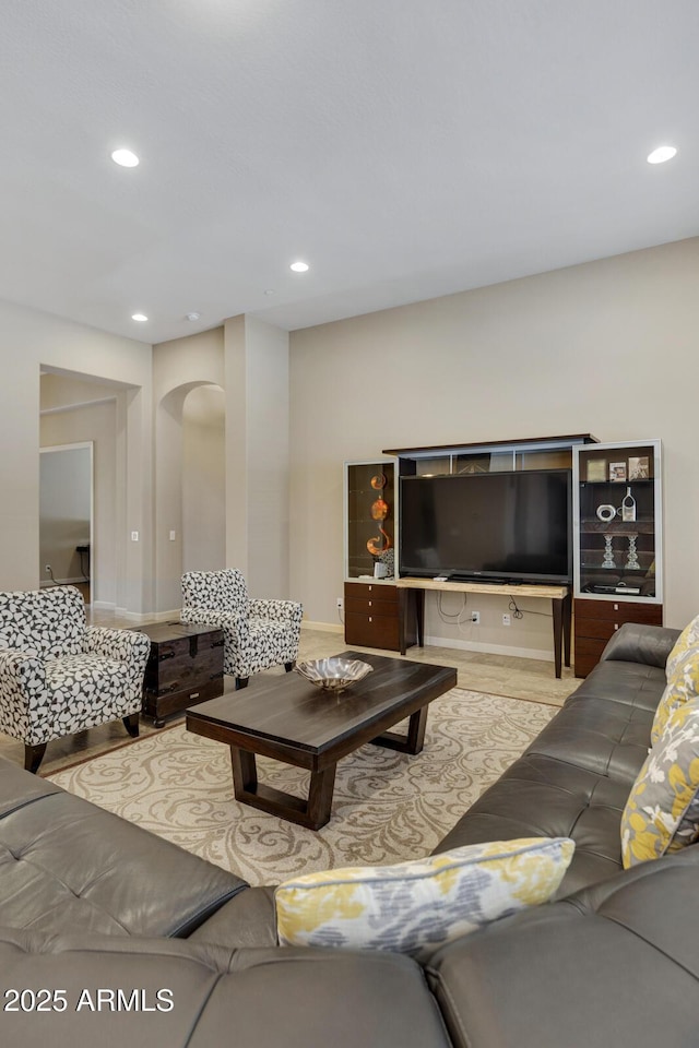 living area with arched walkways, wood finished floors, and recessed lighting