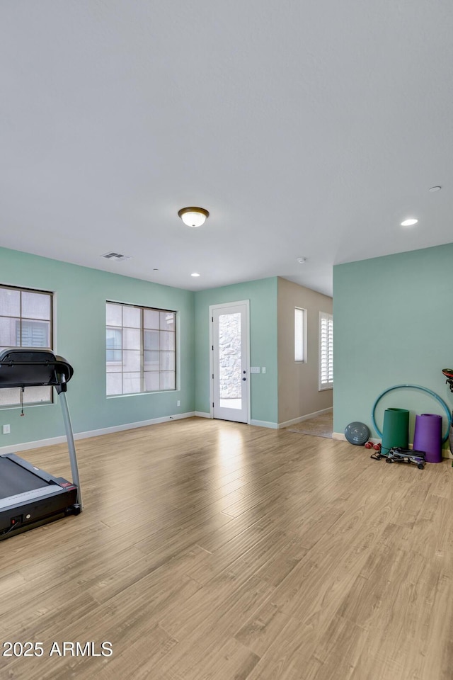 exercise room with light wood-style flooring, visible vents, and baseboards