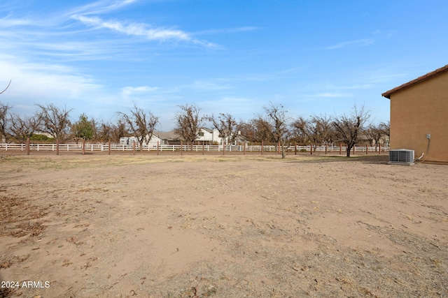 view of yard featuring fence, central AC, and a rural view