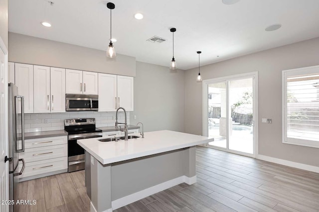 kitchen featuring visible vents, plenty of natural light, a sink, decorative backsplash, and appliances with stainless steel finishes