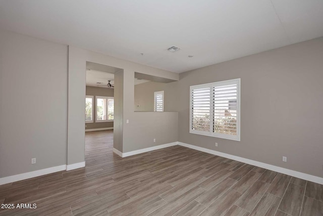 unfurnished room with visible vents, a ceiling fan, baseboards, and wood finished floors