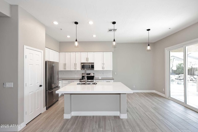 kitchen featuring visible vents, backsplash, light wood-type flooring, white cabinets, and stainless steel appliances