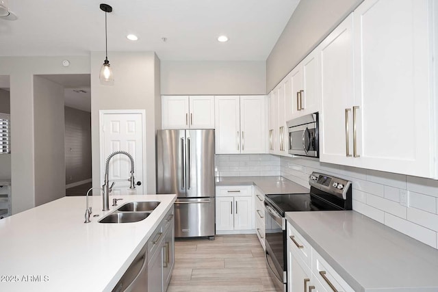 kitchen featuring light countertops, decorative backsplash, hanging light fixtures, stainless steel appliances, and a sink