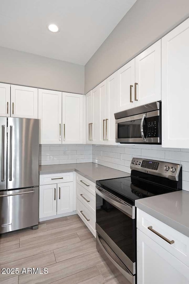 kitchen with backsplash, white cabinetry, and stainless steel appliances